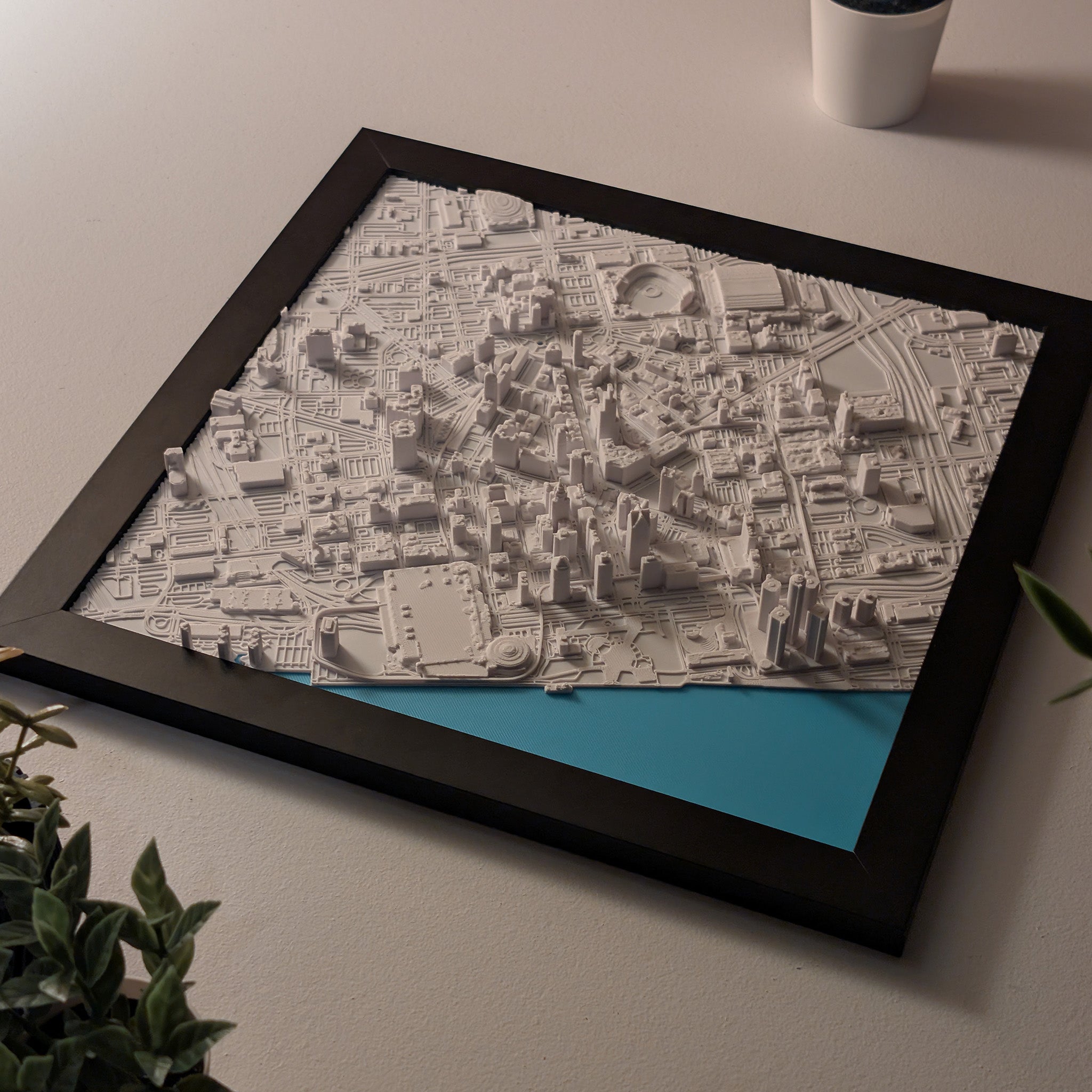 Framed city map on a light surface with a plant and cup in the background