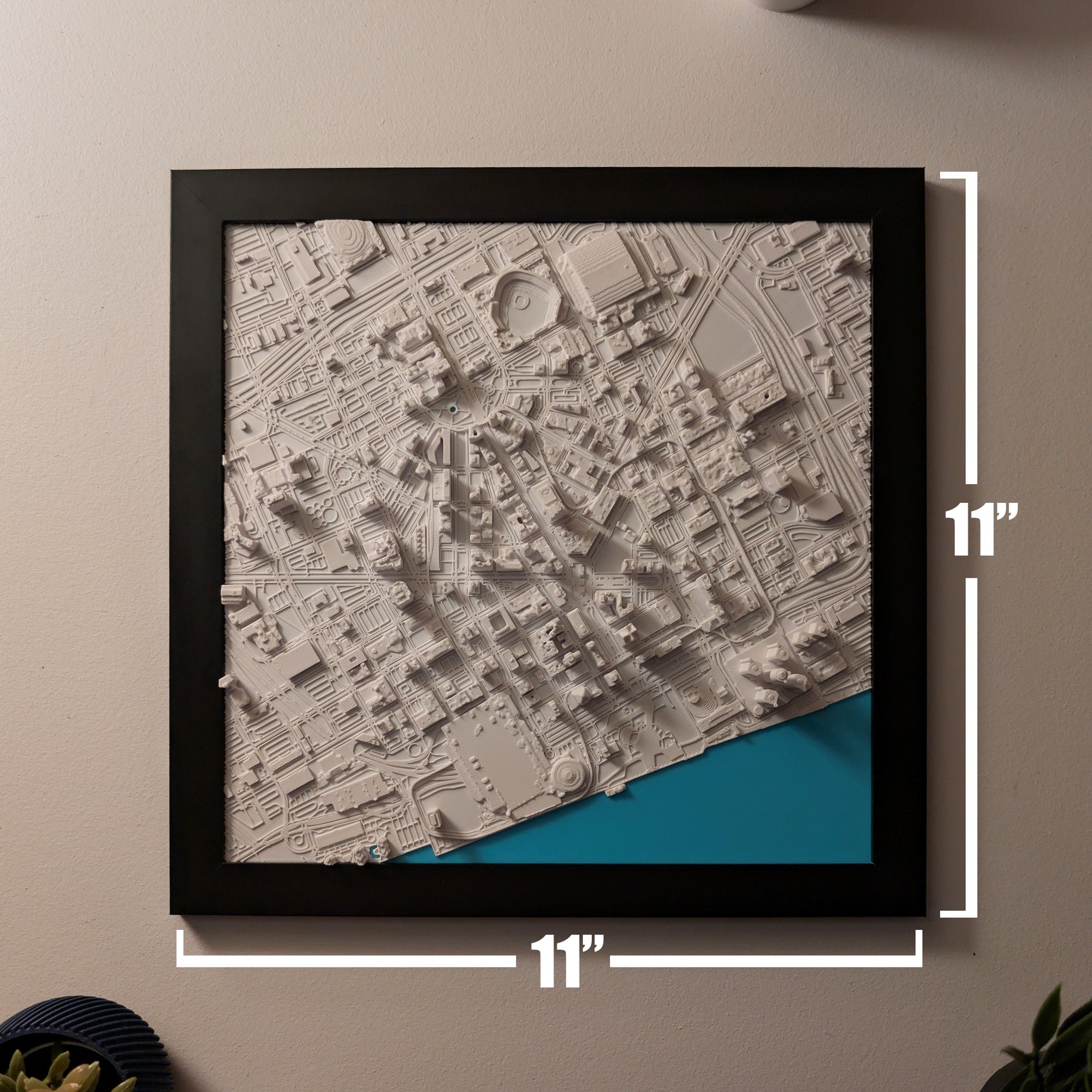 Framed topographic map with dimensions on a beige wall